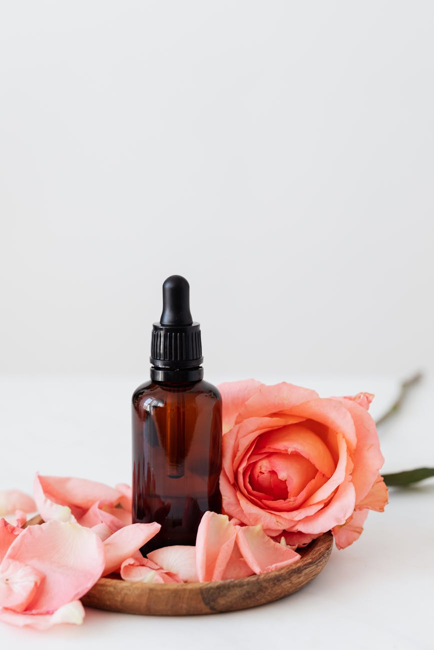 set of cosmetic bottle with pink rose on wooden plate